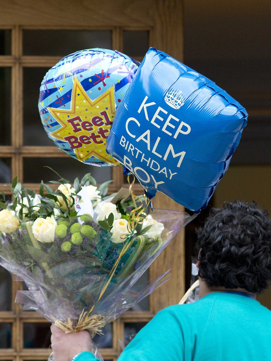 A man arrives with flowers and balloons for Prince Philip at the London Clinic.
