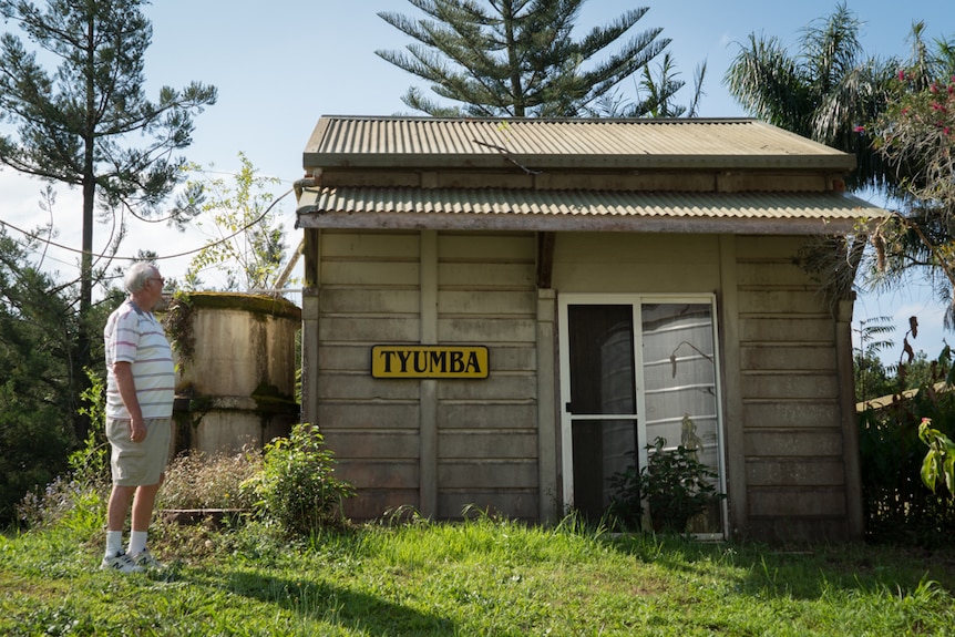 Photography of a tiny prefabricated concrete building between two silos on a Macadamia Farm