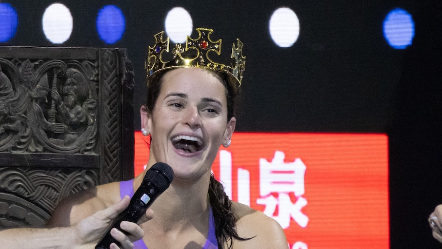 Kaylee McKeown laughs with a crown on her head.