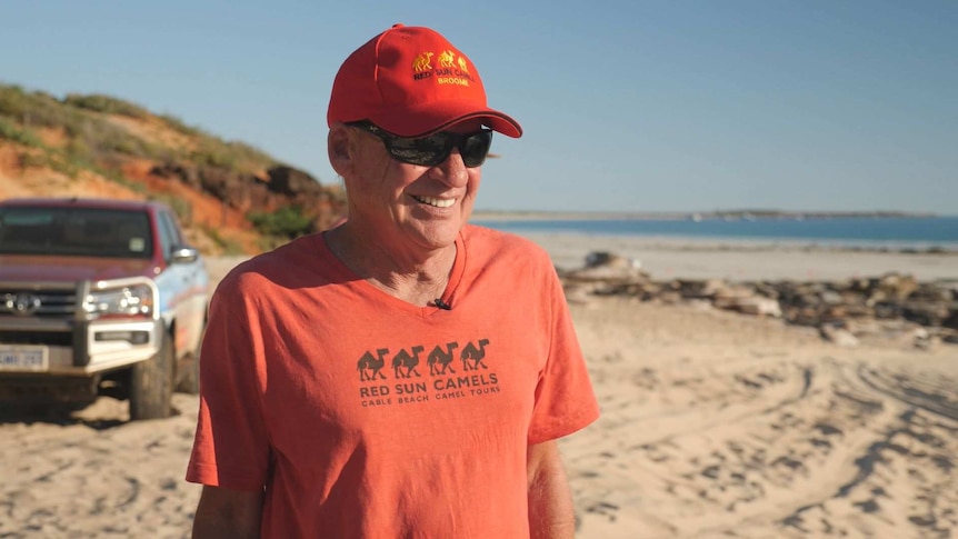 Red Sun Camels owner John Geappen on the beach with a four wheel drive behind.