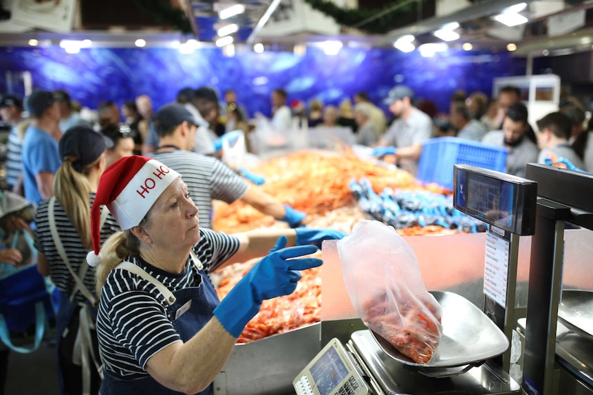 A woman weighing prawns at a fishmonger.