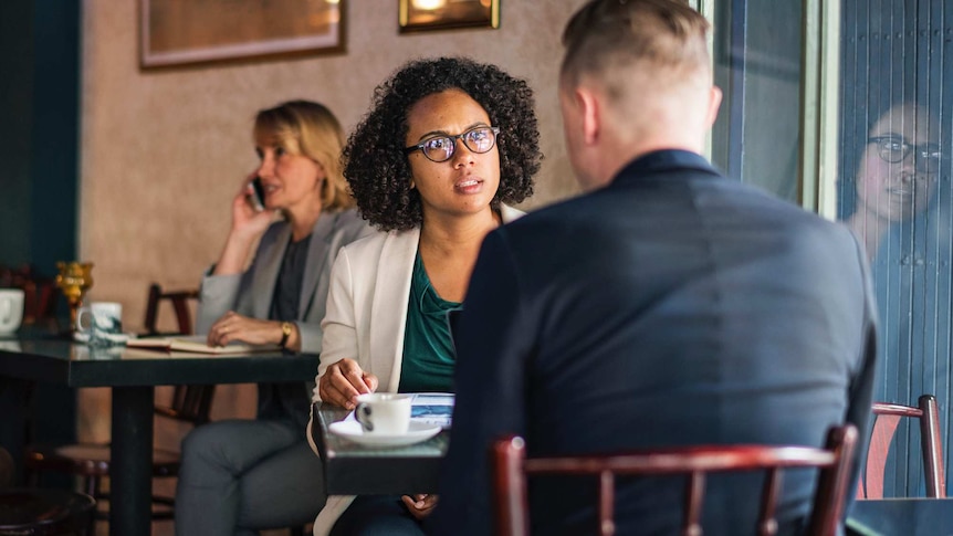 A woman sitting across from a man in a cafe setting to depict racism in online dating.