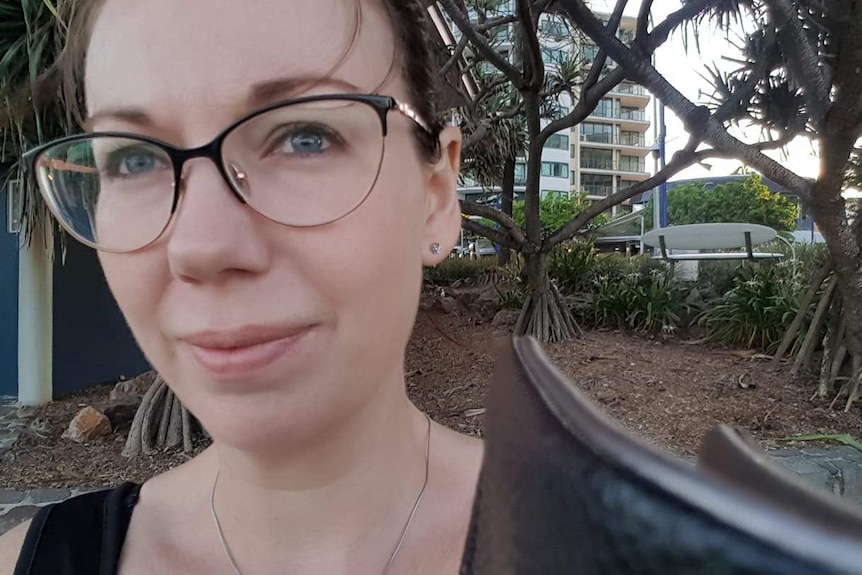 A close-up shot of a woman at a beachside park, looking away from the camera.