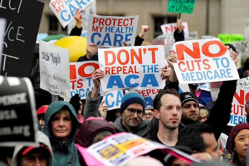 Demonstrators hold signs reading "Don't repeal the ACA" and "No cuts to medicare"