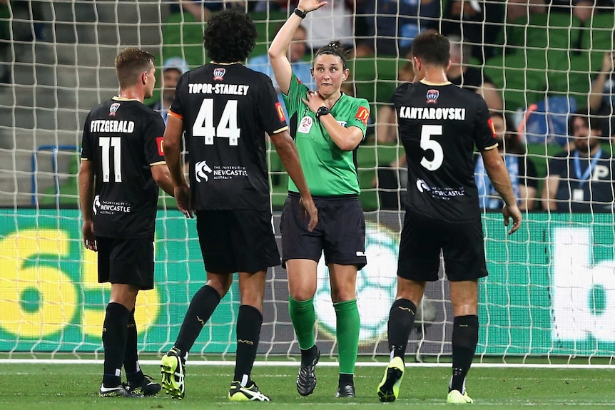 Kate Jacewicz holds her hand up while surrounded by three Newcastle Jets players.