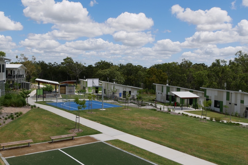 View of a small block of separate buildings, with a basketball court and grass