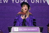 Taylor Swift speaks at lectern during a graduation ceremony.