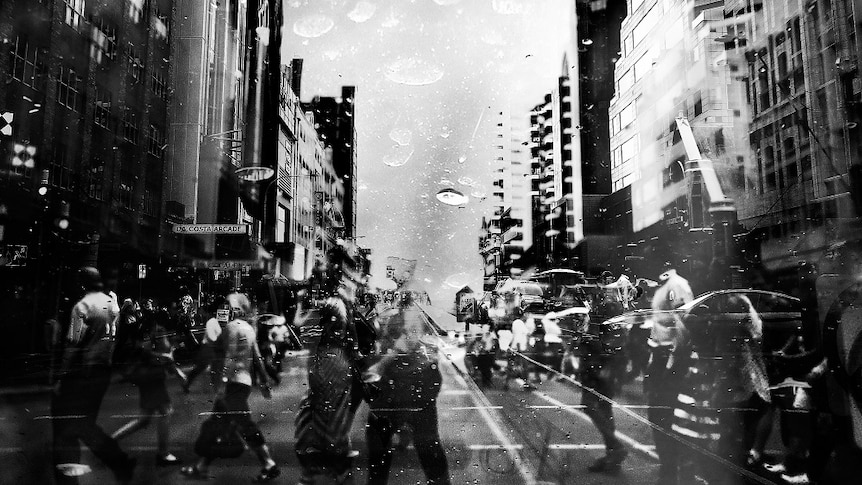 A black and white image of a busy city street seen through a window with raindrops on it.