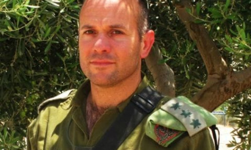 A man in a green army uniform with stars on the shoulder stands outdoors in a portrait.