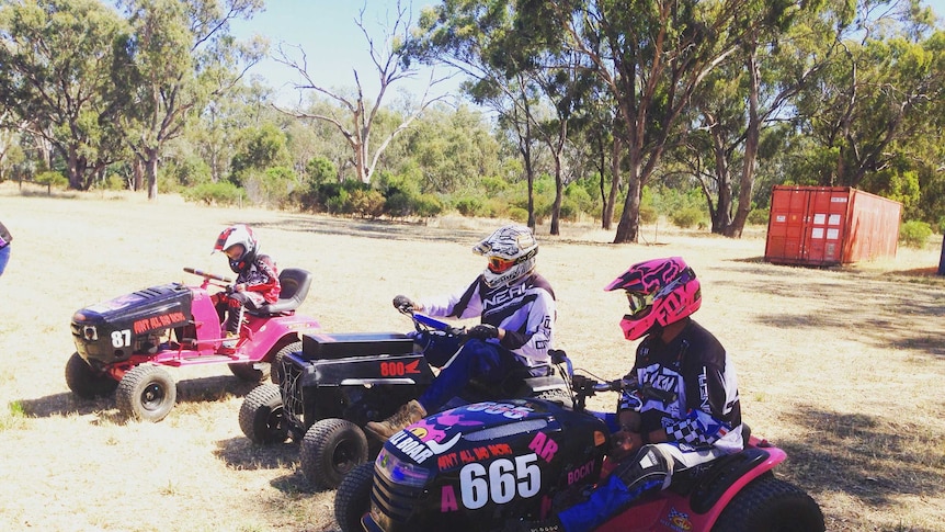 A family sit on their lawn mowers preparing to race.