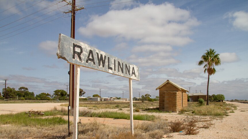 A railway siding reading 'Rawlinna', with buildings in the background.