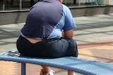 Obese man sits on a bench