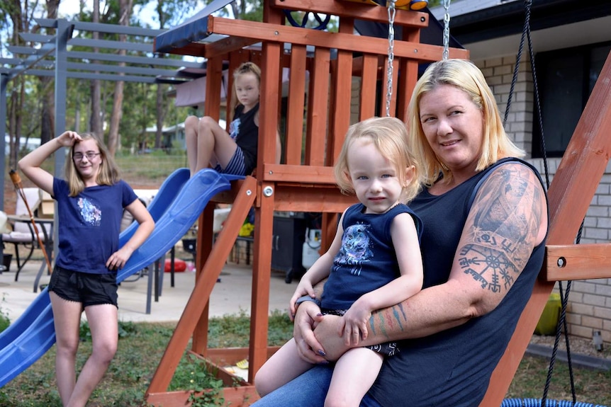 A woman with her three children outside a house