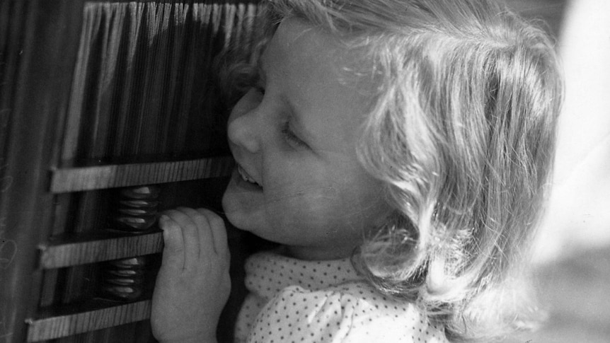 A child listens intently to a radio.