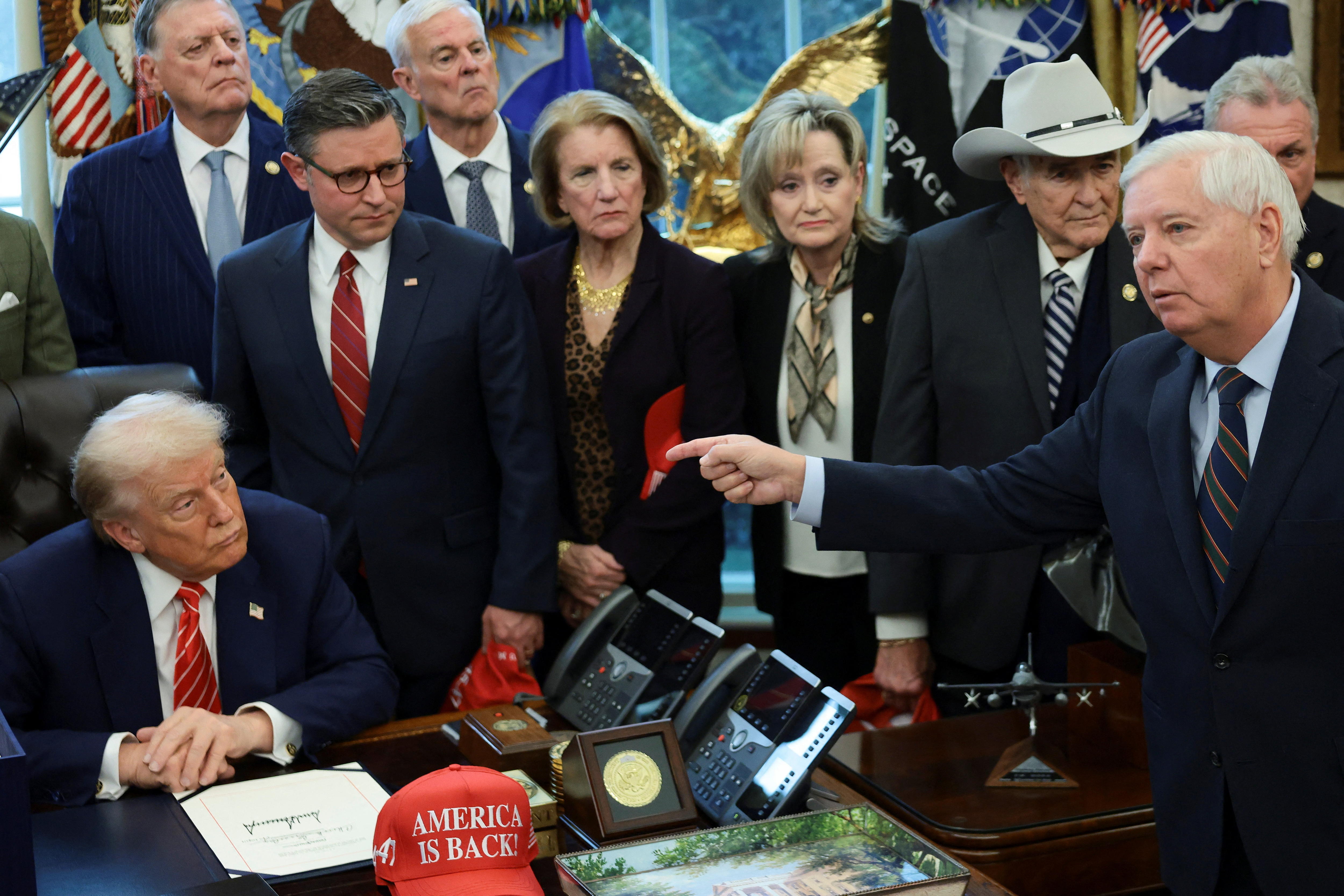 Lindsey Graham speaks beside the Resolute Desk and points at Donald Trump