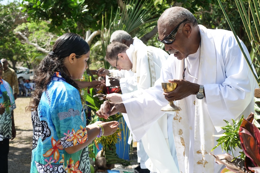 Torres Strait Islander man part of a church service performing holy communion.