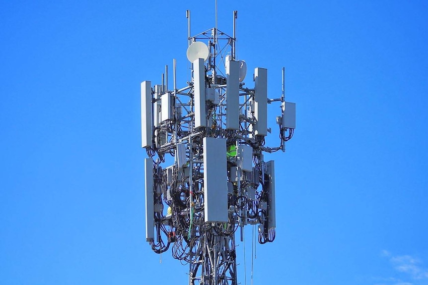 Top of mobile phone tower with bright blue sky backdrop.
