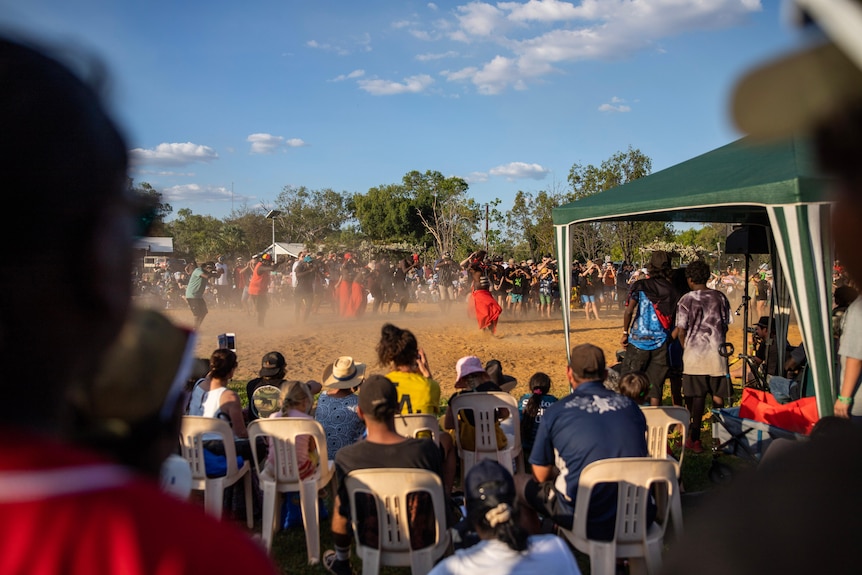 Dancers on sand can be seen through the crowd.