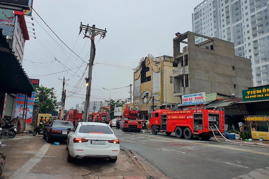 Fire trucks park in a line on the side of a street outside a karaoke parlor following a fire.