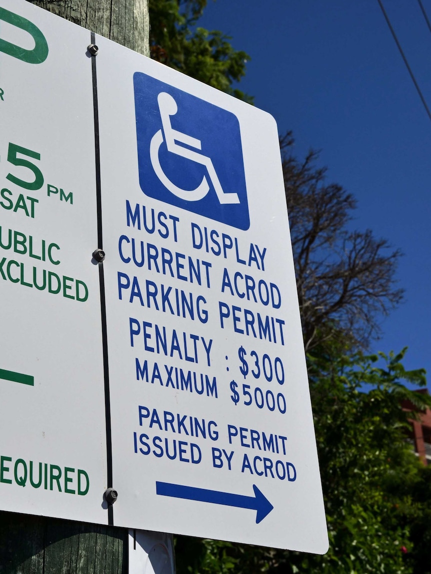 A street sign showing a car parking space for disabled drivers and penalties for improper parking
