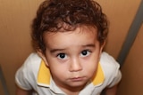 Child looks up at camera with a guilty look