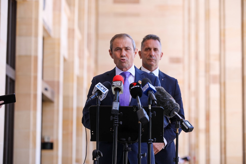 WA Premier Roger Cook speaking at a media conference with Corrective Services Minister Paul Papalia behind him.