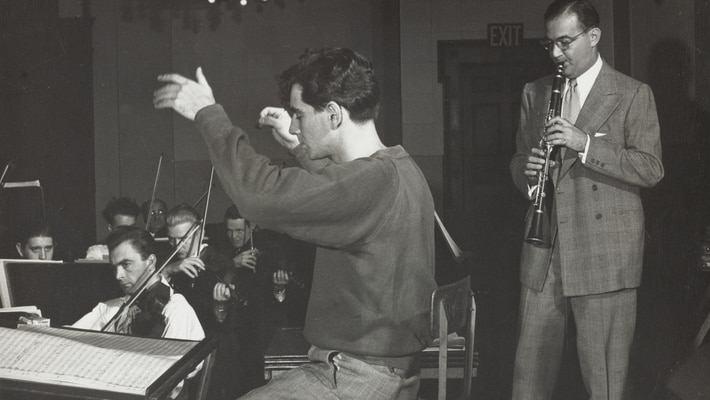 Bernstein sitting on a chair conducting with a string section visible, and Benny Goodman in the background playing clarinet.