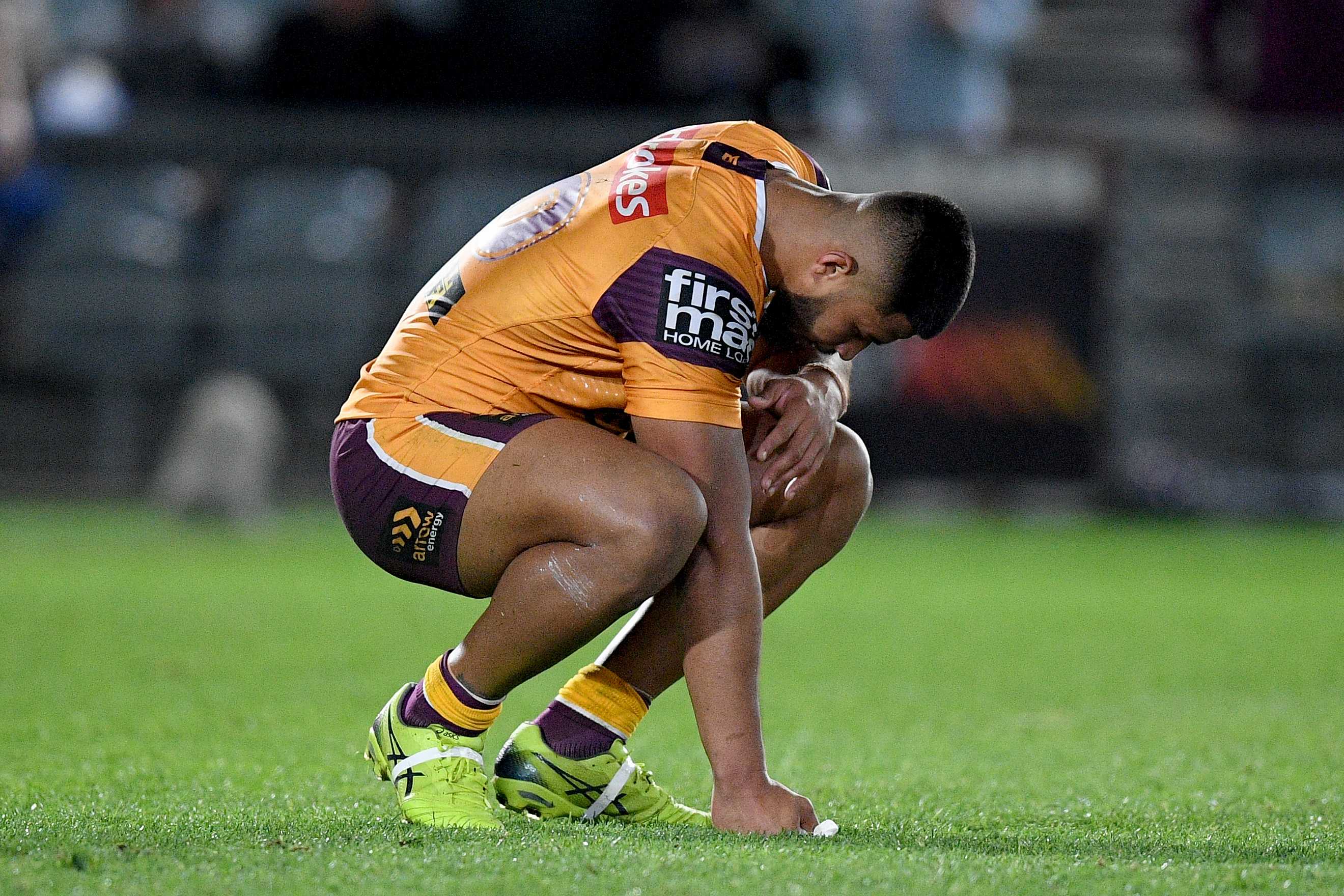 A Brisbane Broncos NRL player crouches on the ground after a loss to the Warriors in Gosford.