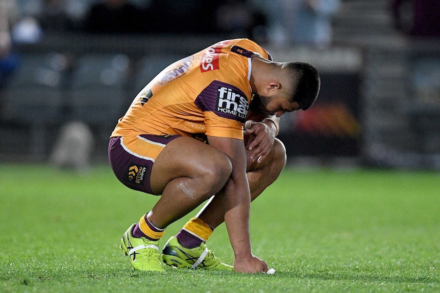 A Brisbane Broncos NRL player crouches on the ground after a loss to the Warriors in Gosford.
