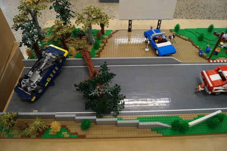 Lego model showing a car crashing into a tree, people watching a drive in movie.