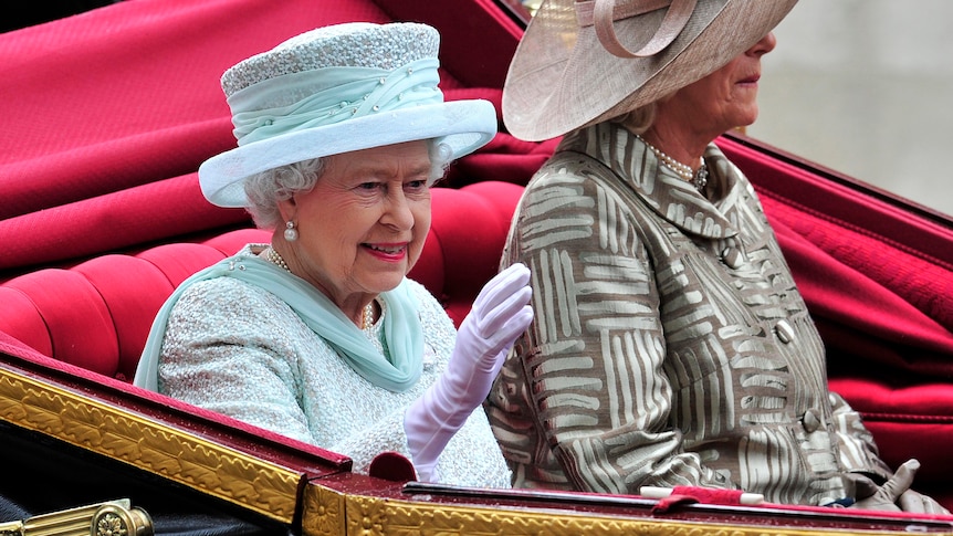 Queen Elizabeth rides in an ornate open carriage.