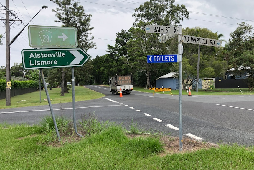 Road signs that point to Alstonville and Lismore at a blocked off road intersection 