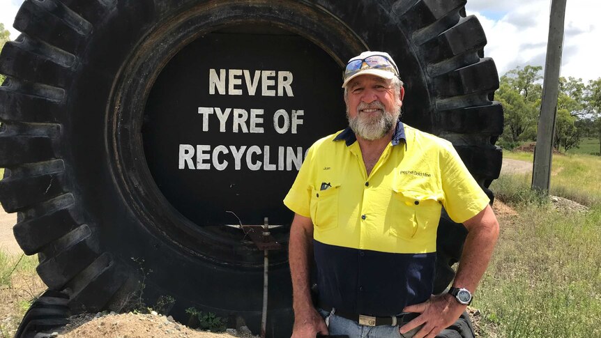 John Parsons standing in front of a large tyre that reads "Never tyre of recycling"