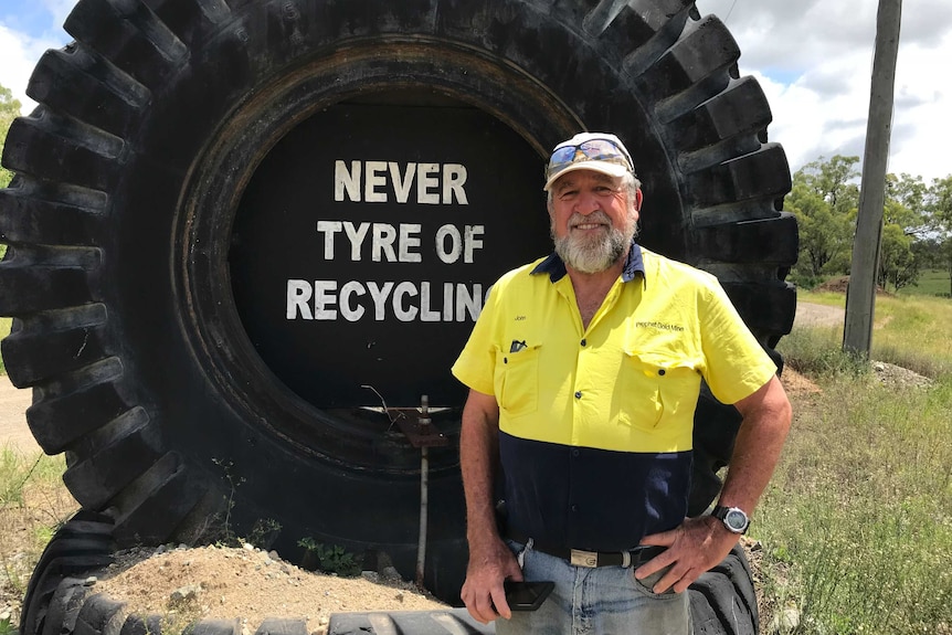 John Parsons standing in front of a large tyre that reads "Never tyre of recycling"