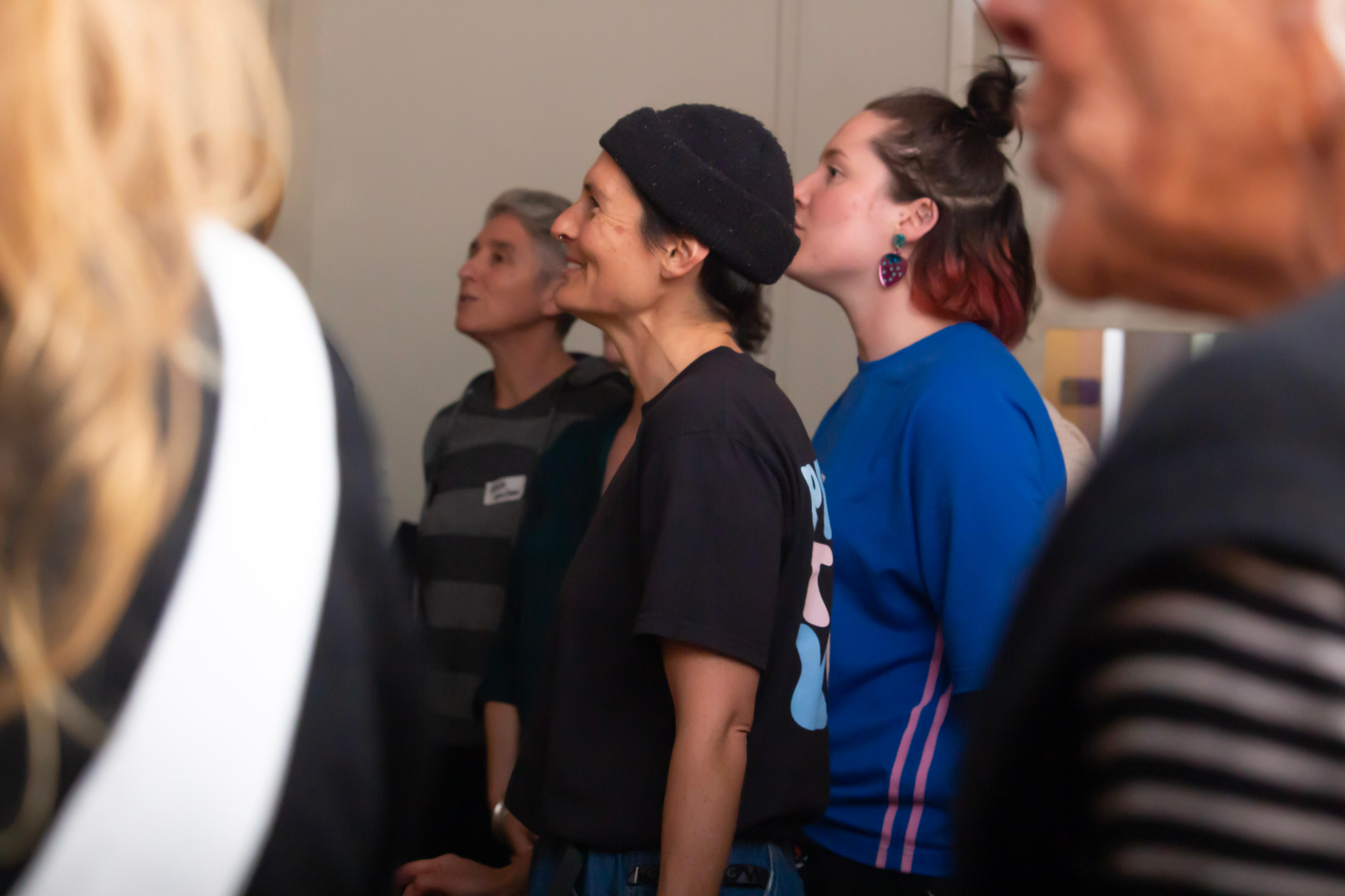 Side view of a group of people singing in a room.