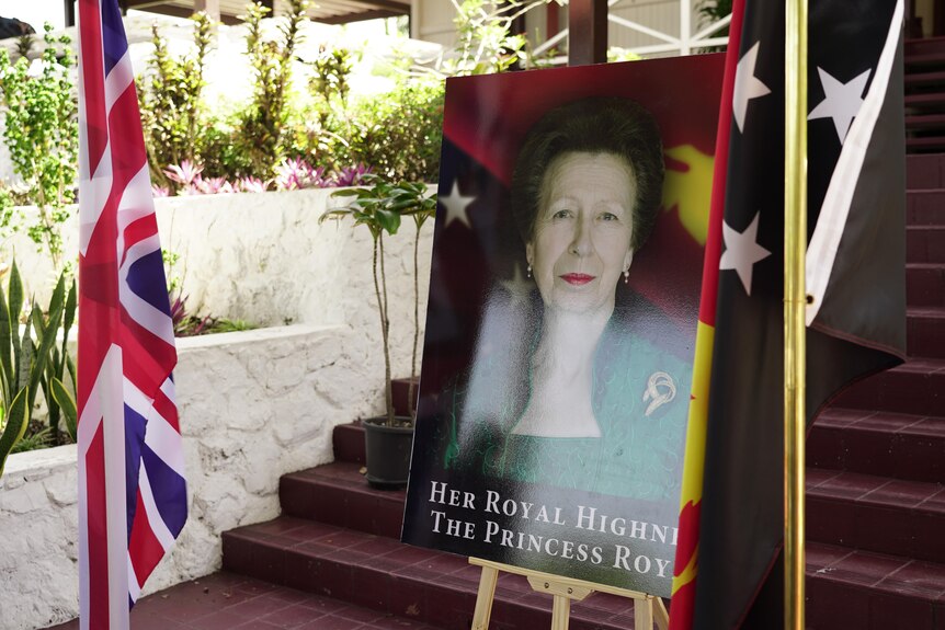 A poster of Princess Anne flanked by a Union Jack flag and PNG's flag
