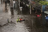 People wade through flooded streets near the Chao Praya river in Bangkok on October 28, 2011.