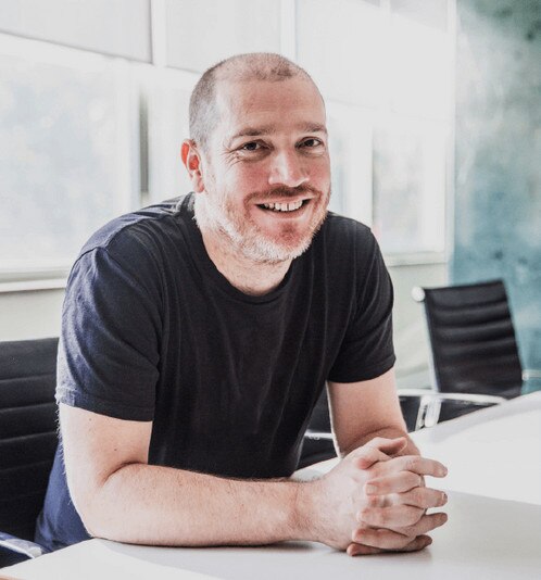 Dom Price sits at a conference table.