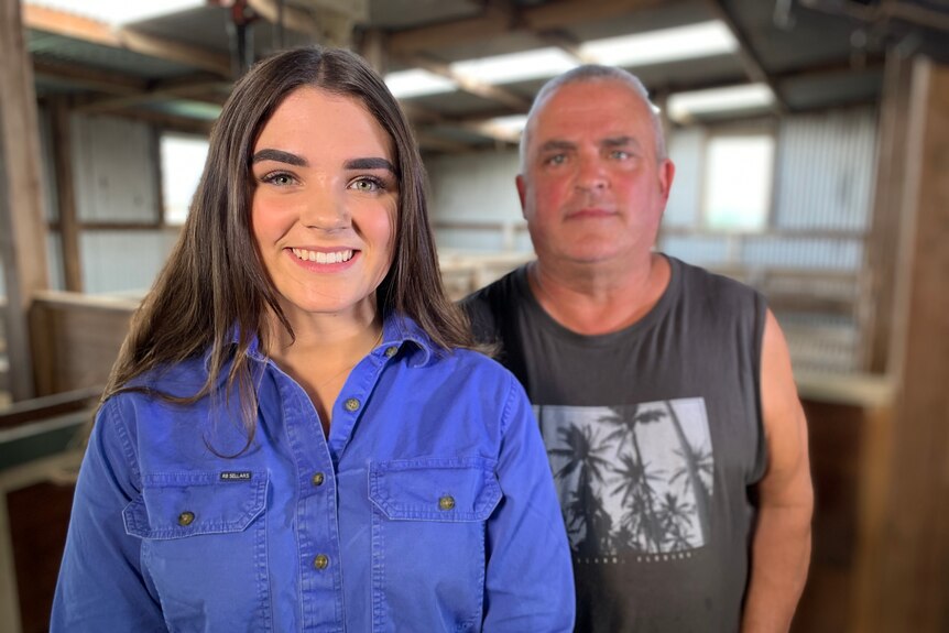 a daughter and father standing next to each other in wool shed