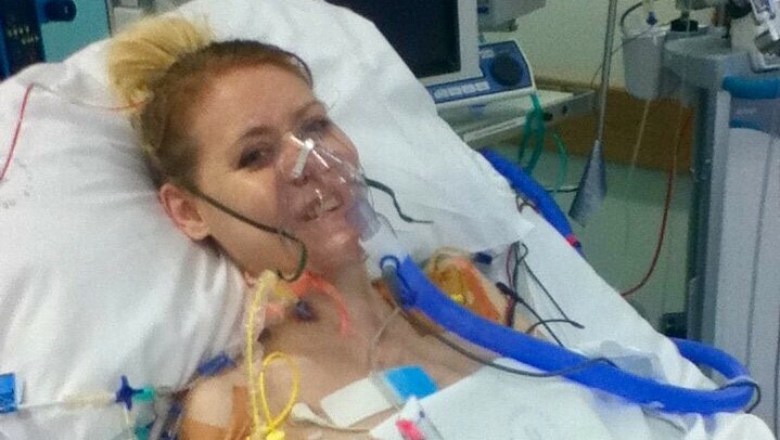 A woman in a hospital bed with an oxygen mask on.