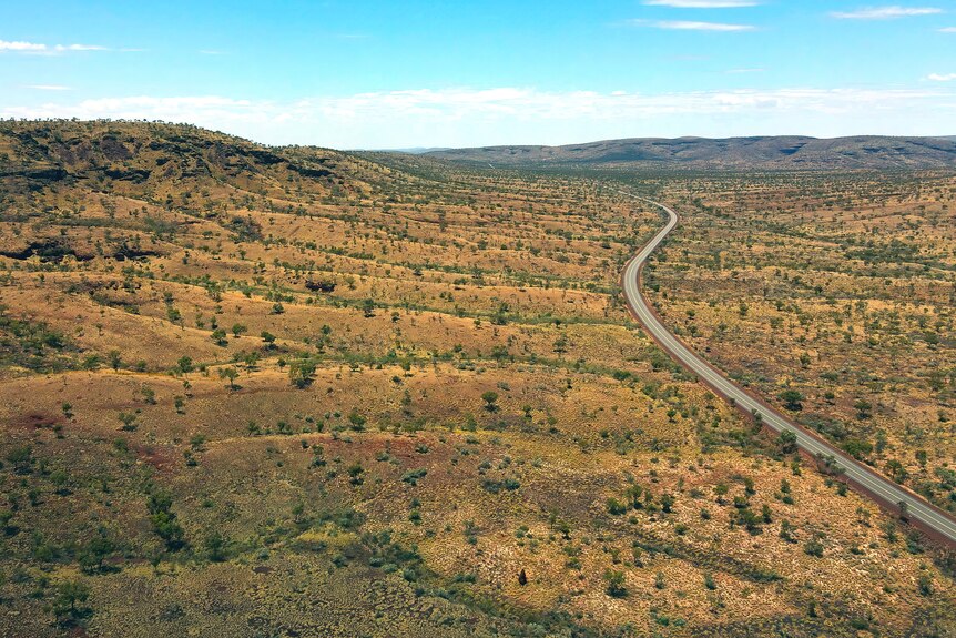 An aerial wide shot of a main road cutting through a barren landscape