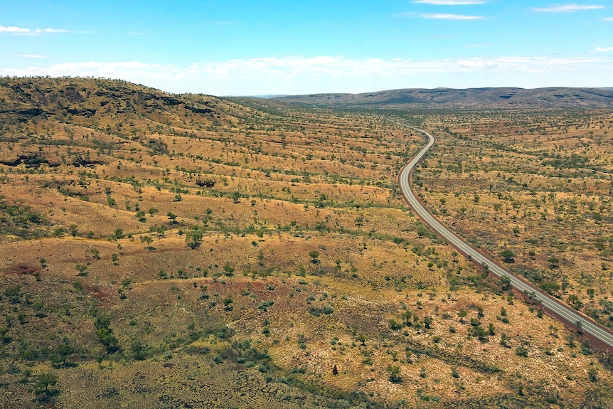 An aerial wide shot of a main road cutting through a barren landscape