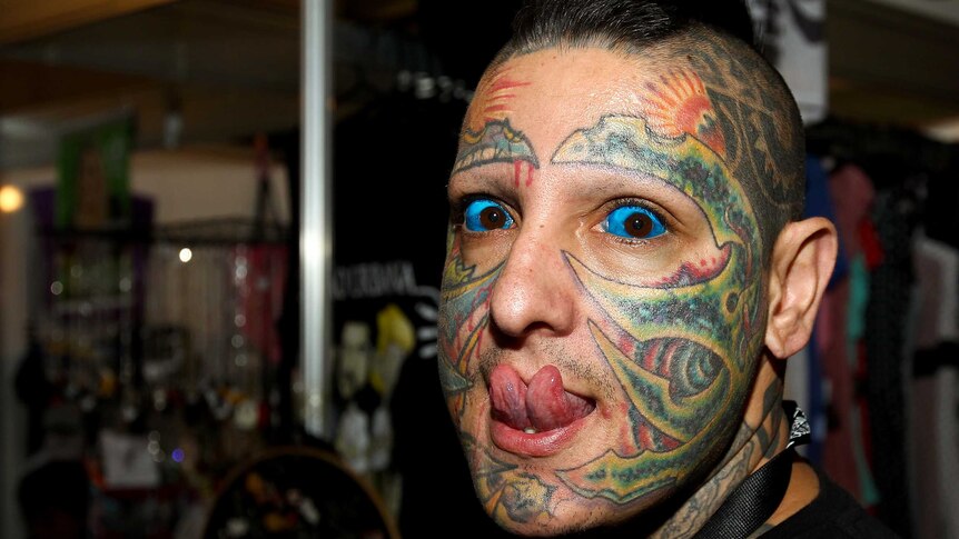 A man with a forked tongue, facial tattoos and blue eyeballs