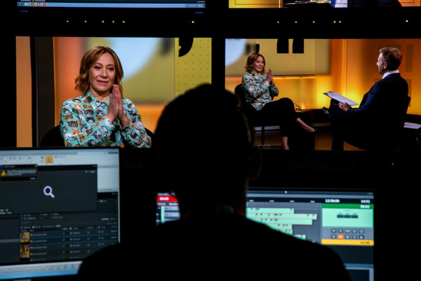 Studio monitors showing Hutcheon being interviewed.