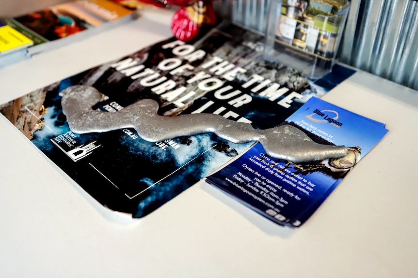 A melted piece of metal sits atop a set of brochures at an oyster shop