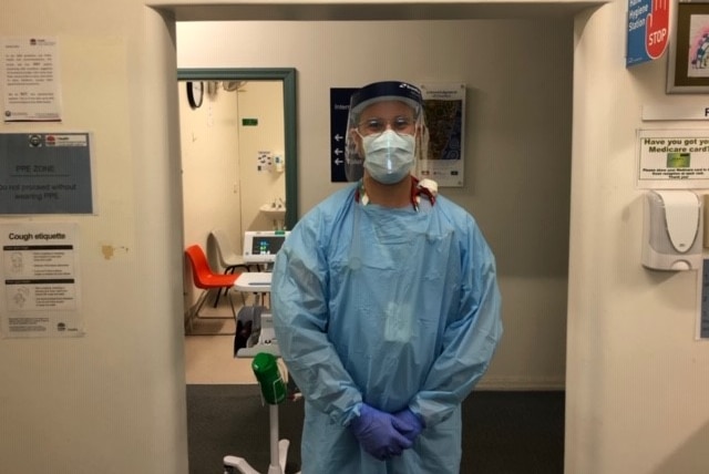 Dr Michael Krasovitsky standing in an open doorway in a hospital wearing protective goggles, mask, gloves and apron