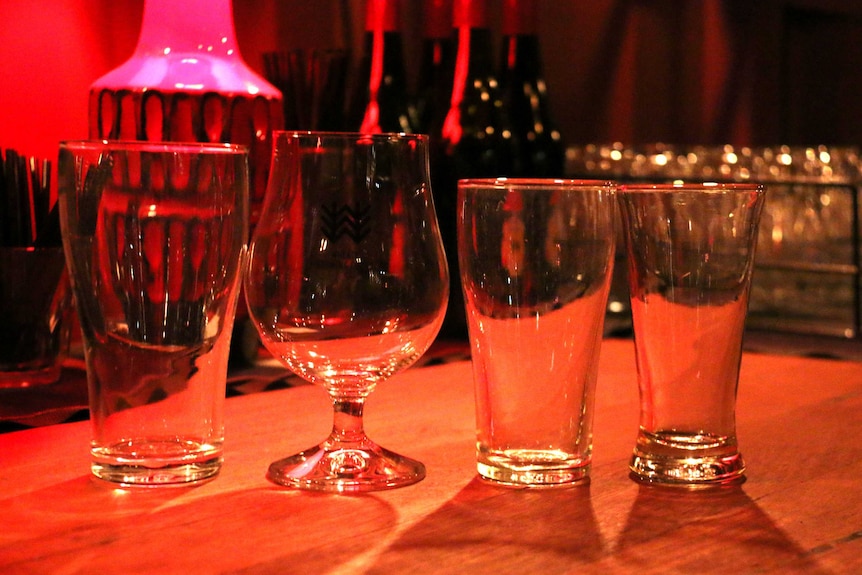 Four beer glasses sitting on a table.