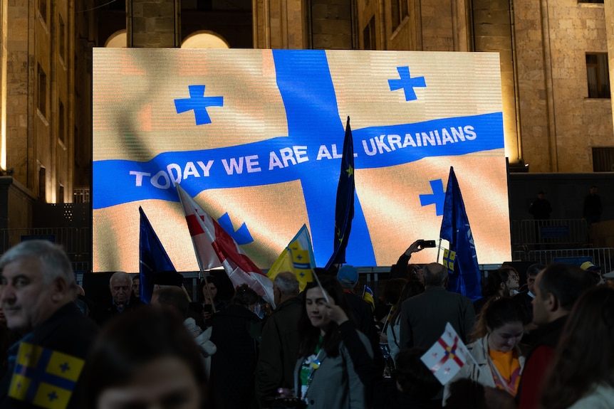 Protesters hold a sign reading 'we are all Ukrainian'.