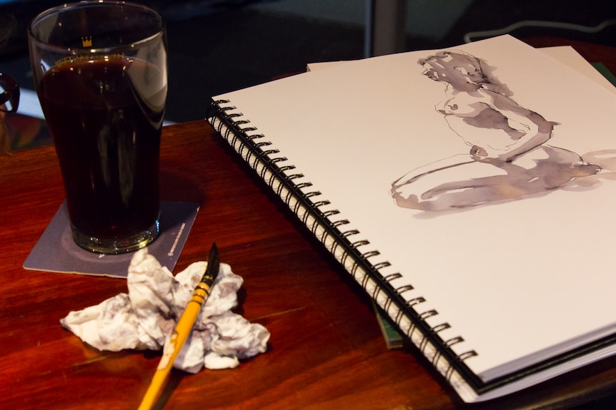 Life drawing of a nude female figure next to a beer glass and paint brush.