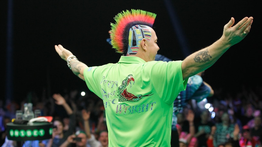 Peter Wright stands with his arms outstretched looking at the crowd with a pattern in his hair.
